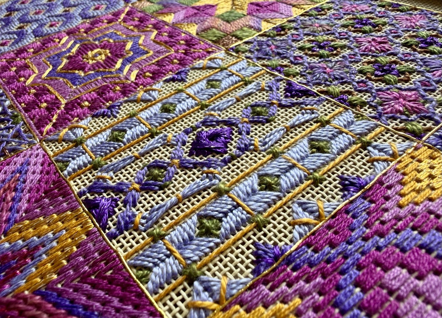 Macro view of textured needlepoint stitches in The Bazaar Collection, with open canvas, dimensional threadwork, and metallic accents.